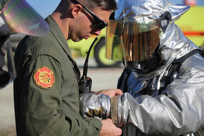 Sgt. Aaron Mack adjusts Cpl. Miguel Avalos’s gear during a live fire training event on Marine Corps Air Station New River, N.C., Jan. 19, 2017. The training used propane and piping to simulate fires on the interior and exterior of an aircraft. Mack is an assistant section leader with Marine Corps Air Station New River’s Aircraft Rescue Firefighting division. Avalos is a rescueman with Marine Corps Air Station New River’s Aircraft Rescue Firefighting division. (U.S. Marine Corps photo by Cpl. Melodie Snarr)