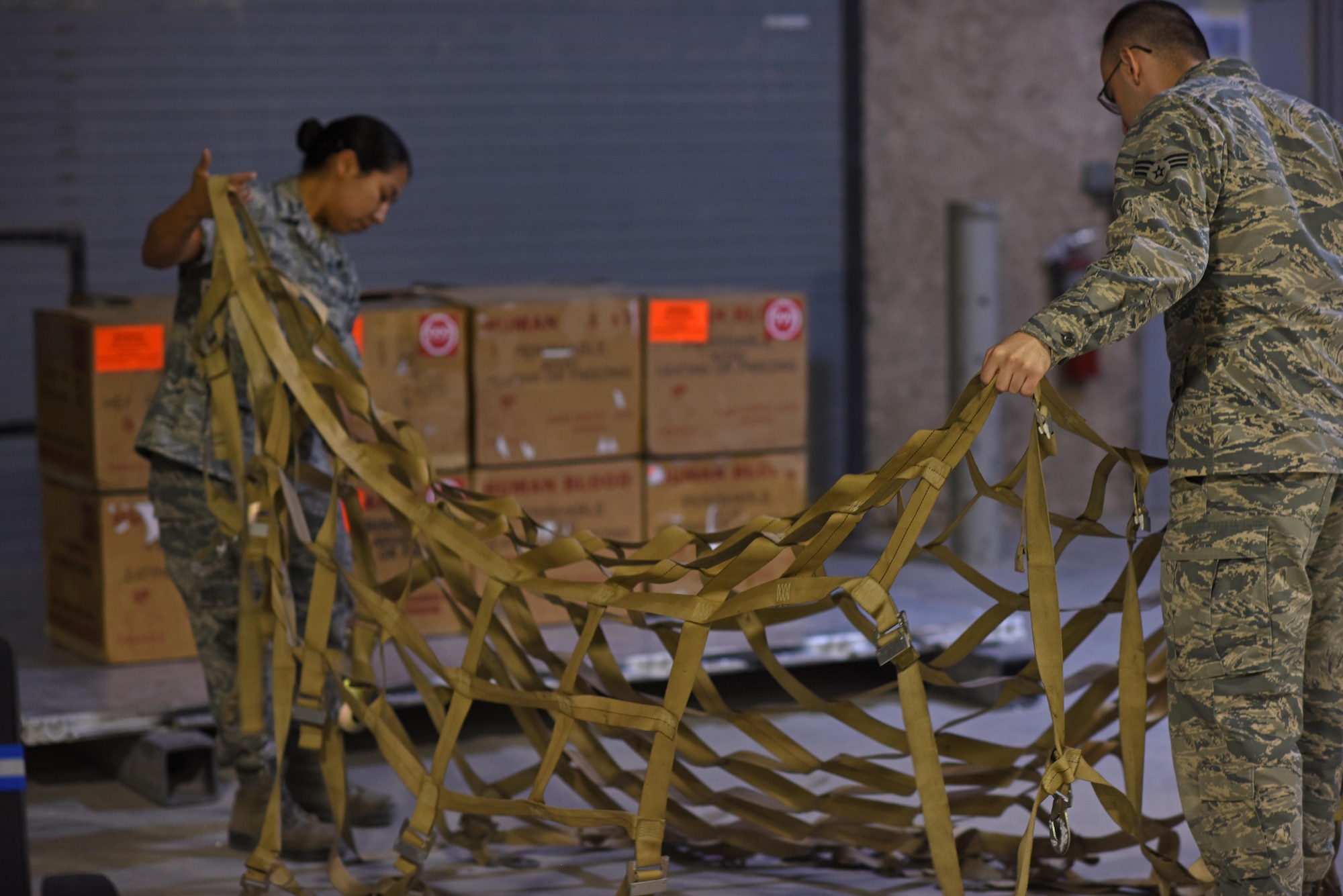U.S. Air Force Senior Airman Celina Garcia, a medical logistics technician, left, and U.S. Air Force Senior Airman Dean Blackmore, a medical laboratory technician, both with the 379th Expeditionary Medical Group blood transshipment center, untangle cargo straps to secure blood shipping containers onto a pallet at Al Udeid Air Base, Qatar, Jan. 27, 2017. These Airmen operate the only blood transshipment center for the entire Central Command area of responsibility. (U.S. Air Force photo by Senior Airman Cynthia A. Innocenti)