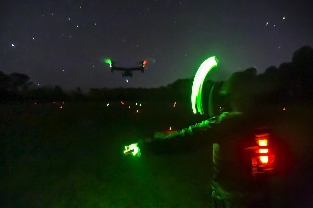 A Marine uses chemical light sticks to direct an MV-22B Osprey into a landing zone during an external lift exercise at Camp Lejeune, N.C., Jan. 24, 2017. An external lift provides a fast, effective way to move cargo and other heavy equipment, increasing the logistic capabilities of ground elements. The Marine is assigned to Combat Logistics Battalion 26. Marine Corps photo by Lance Cpl. Damarko Bones