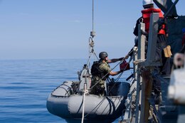 Boatswain's Mate 1st Class Alan Farthing, assigned to the Arleigh Burke-class guided-missile destroyer USS Cole (DDG 67), places a container of JP-5 fuel into a rigid-hull inflatable boat during an approach and assist visit in response to a distress call from an Iranian-flagged dhow. Cole is deployed in the U.S. 5th Fleet area of operations in support of maritime security operations and theater security cooperation efforts.
