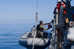 Boatswain's Mate 1st Class Alan Farthing, assigned to the Arleigh Burke-class guided-missile destroyer USS Cole (DDG 67), places a container of JP-5 fuel into a rigid-hull inflatable boat during an approach and assist visit in response to a distress call from an Iranian-flagged dhow. Cole is deployed in the U.S. 5th Fleet area of operations in support of maritime security operations and theater security cooperation efforts.
