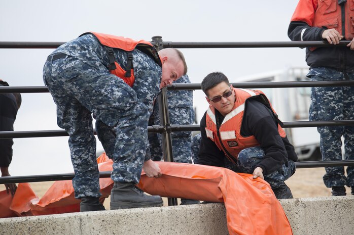 U.S. Navy Engineman 2nd Class, Jason McNealy, left, and U.S. Navy Boatswain’s Mate 2nd Class, Matthew Mora, with harbor operations, right, deploy a boom into the south retention pond during a spill training exercise at Marine Corps Air Station Iwakuni, Japan, Jan. 27, 2017.  The boom is used during spills to corral oil and fuel into controlled areas. The air station conducts an annual spill training exercise to evaluate response time, efficiency and to prepare for any spills that may occur. (U.S. Marine Corps photo by Lance Cpl. Joseph Abrego)