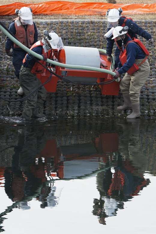 Facilities personnel place a drum skimmer in the south retention pond during a spill training exercise at Marine Corps Air Station Iwakuni, Japan, Jan. 27, 2017. The drum skimmer is used to skim the top of the water and pump oil and fuel into an evacuation truck where it can be secured. The air station conducts an annual spill training exercise to evaluate response time, efficiency and to prepare for any spills that may occur. (U.S. Marine Corps photo by Lance Cpl. Joseph Abrego)