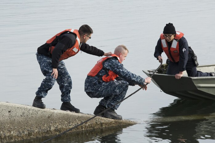 U.S. Navy Boatswain’s Mate 2nd Class Matthew Mora, left, and U.S. Navy Engineman 2nd Class, Jason McNealy, with harbor operations, right, work together to get a rope to U.S. Navy Engineman 3rd Class Elizabeth Rodriguez, with harbor operations, during a spill training exercise at Marine Corps Air Station Iwakuni, Japan, Jan. 27, 2017. The air station conducts an annual spill training exercise to evaluate response time, efficiency and to prepare for any spills that may occur. (U.S. Marine Corps photo by Lance Cpl. Joseph Abrego)