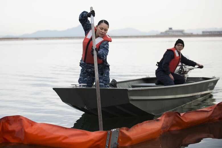 U.S. Navy Engineman 3rd Class Yajaira Armenta Navarro, left,  and U.S. Navy Engineman 3rd Class Elizabeth Rodriguez, right, with harbor operations, work together to retrieve a boom during a spill training exercise at Marine Corps Air Station Iwakuni, Japan, Jan. 27, 2017. The boom is used during spills to corral oil and fuel into controlled areas. The air station conducts an annual spill training exercise to evaluate response time, efficiency and to prepare for any spills that may occur. (U.S. Marine Corps photo by Lance Cpl. Joseph Abrego)