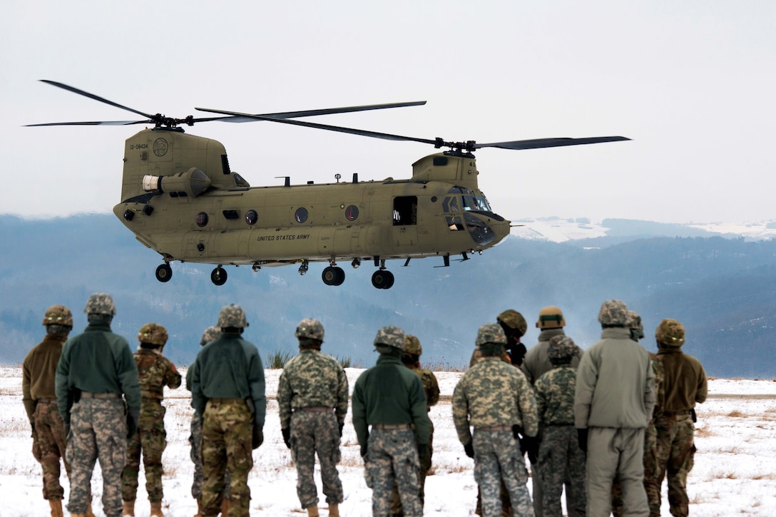 Soldiers watch as a CH-47 Chinook helicopter approaches before participating in slingload training at the Baumholder Military Training Area in Baumholder, Germany, Jan. 26, 2017. The soldiers are assigned to the 8th Medical Company. The helicopter crew is assigned to Company B, 1st Battalion, 214th Aviation Regiment. Army photo by Erich Backes 
