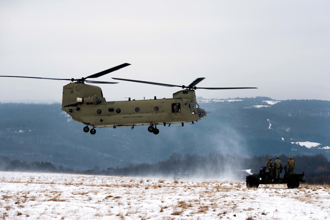 Soldiers waiting in a Humvee watch as a CH-47 Chinook helicopter approaches before taking part in slingload training at the Baumholder Military Training Area in Baumholder, Germany, Jan. 26, 2017. The Humvee will be used during the slingload training. Army photo by Erich Backes