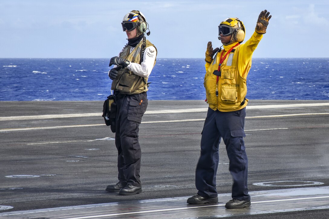 Navy Petty Officers 2nd Class Jacob Letendre, left, and Andre Taylor direct an F/A-18F Super Hornet aircraft on the flight deck aboard the aircraft carrier USS Carl Vinson in the Pacific Ocean, Jan. 25, 2017. Letendre is an aviation electronics technician and Taylor is an aviation boatswains mate (handling) assigned to Strike Fighter Squadron 2. Navy Photo by Seaman Jake Cannady