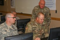 (Left to right) Sgt. 1st Class Kevin Deon, Sgt. 1st Class Matthew Highsmith and Master Sgt. John Gross (standing) work together on the accreditation block of instruction as part of the 80th Training Command's first Quality Assurance Officer course at Grand Prairie, Texas, Jan. 24, 2017.