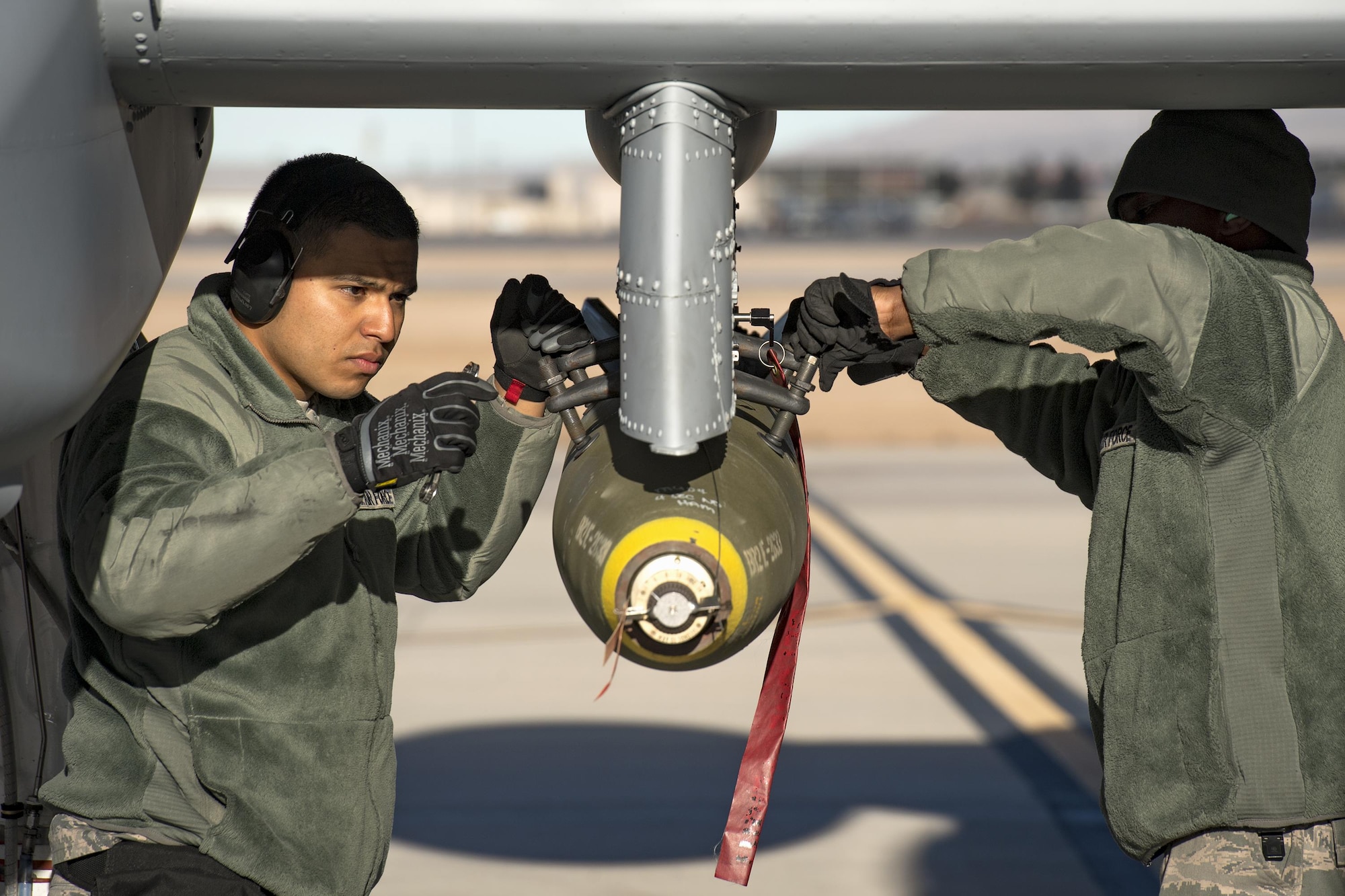 Airman First Class Carlos Quintanilla, left, and Staff Sgt. Tayrell Washington, 74th Aircraft Maintenance Unit weapons load team members, secure a Mark 82 general purpose bomb to the bottom of an A-10C Thunderbolt II during Green Flag-West 17-03, Jan. 24, 2017, at Nellis Air Force Base, Nev. Weapons Airmen enabled joint force training during the two-week exercise by loading weapons, inspecting jets and maintaining munitions systems. Some of the live munitions included the Mark 82 and 84 general purpose bombs, high-explosive incendiary 30mm rounds and the 500 pound GBU-12 Paveway II laser-guided bomb. (U.S. Air Force photo by Staff Sgt. Ryan Callaghan)
