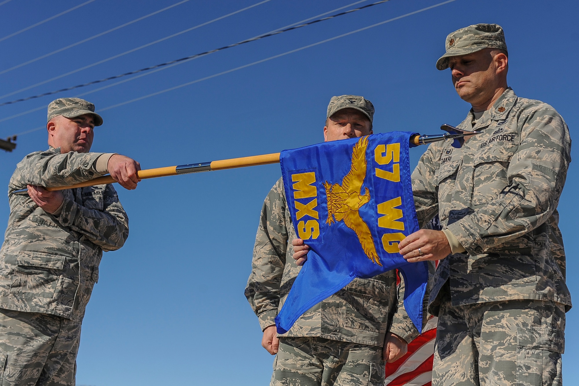 Maj. Matthew Zakri, 57th Munitions Squadron commander, prepares to furl the 57th Maintenance Squadron guidon during a redesignation ceremony at Nellis Air Force Base, Nev., Jan. 27, 2017. During the ceremony, the 57th MXS was inactivated and all of its former Airmen stood up the newly activated 57th MUNS.