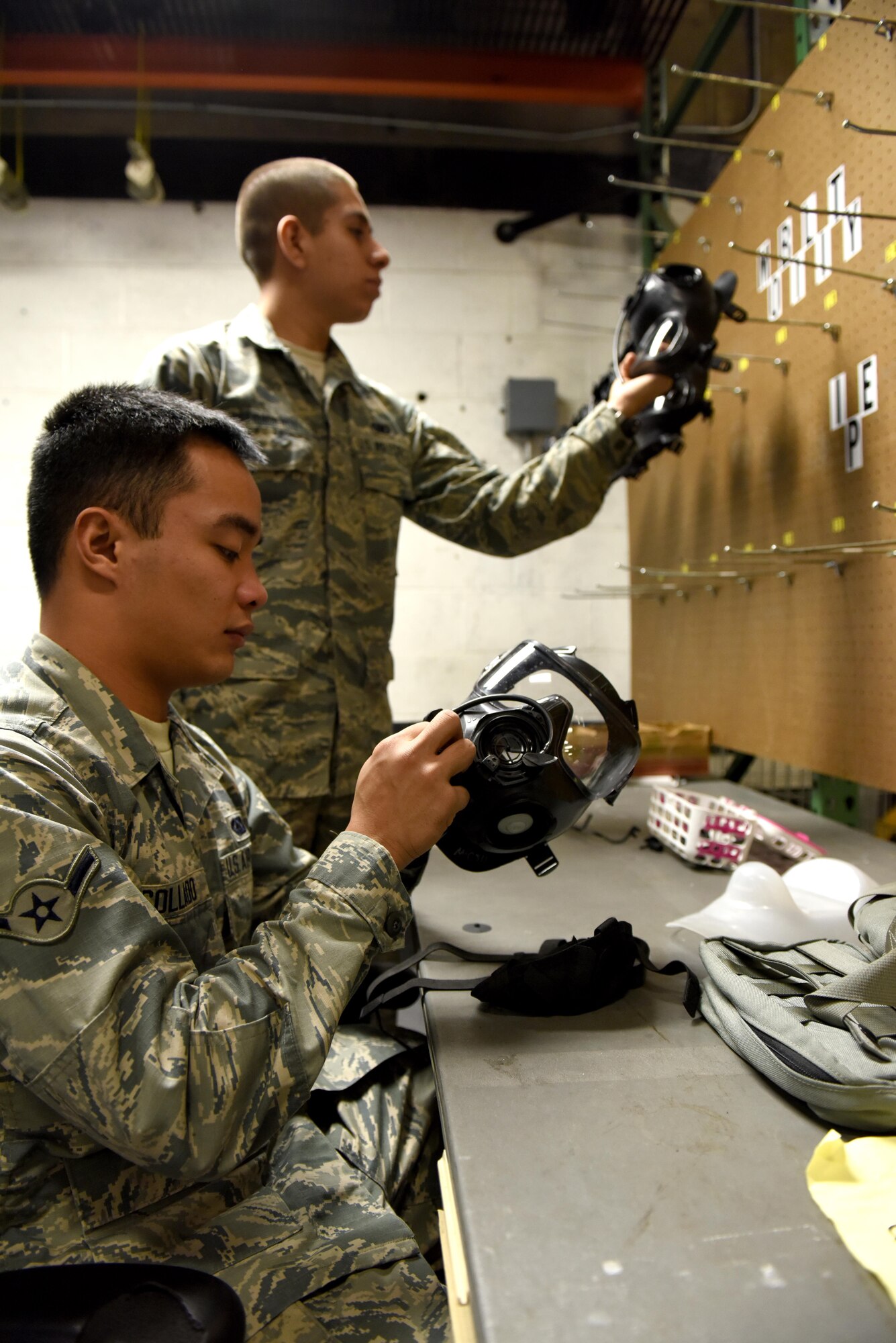 U.S. Air Force Airman Joerimer Collado, left, and Airman Aleandro Pust Cunibertti, individual protective equipment (IPE) specialists assigned to the 509th Logistics Readiness Squadron, disassemble gas masks at Whiteman Air Force Base, Mo., Jan. 18, 2017. Once an individual turns in their protective gear, the gas masks are taken apart to be sterilized and inspected. (U.S. Air Force photo by Senior Airman Danielle Quilla)