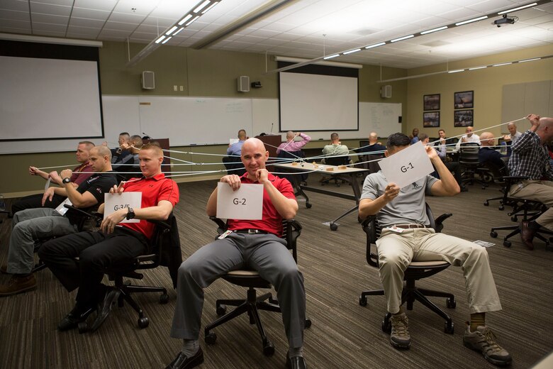 Senior leaders from across Marine Forces Reserve each represent a department in a unit as they work together complete an exercise during the Senior Leadership Workshop aboard Marine Corps Support Facility New Orleans, Jan. 23-26, 2017. The exercise required the Marines and Sailors to work together to accomplish the mission of stacking the wooden blocks on the table using the ropes in hand. The leaders participated in multiple exercises and discussions that address differences in leadership styles, perspectives, experiences, backgrounds and more. The workshop aims to emphasize the importance of open communication and equal opportunity, and to demonstrate their effects on unit cohesion, mission accomplishment and mission readiness. (U.S. Marine Corps photo by Sgt. Sara Graham) 