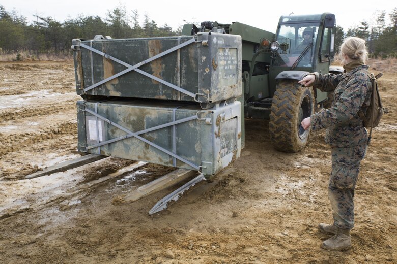 U.S. Marine Corps Lance Cpl. Jeni Ridgell, an expeditionary airfield technician with Marine Wing Support Squadron 171, directs Lance Cpl. Kevin Hodson, an engineer equipment operator with MWSS-171, as he moves crates of generation 2 aluminum matting during exercise Kamoshika Wrath 17-1 at Haramura Maneuver Area, Hiroshima, Japan, Jan. 27, 2017. The Marines worked through inclement weather conditions and a short timeline to build a 96-foot by 96-foot vertical takeoff and landing pad. The exercise is a biannual, unit-level training exercise that is primarily focused on establishing a forward operating base and providing airfield operation services. MWSS-171 trains throughout the year completing exercises like Kamoshika Wrath to enhance their technical skills, field experience and military occupational specialty capability. (U.S. Marine Corps photo by Cpl. Donato Maffin)