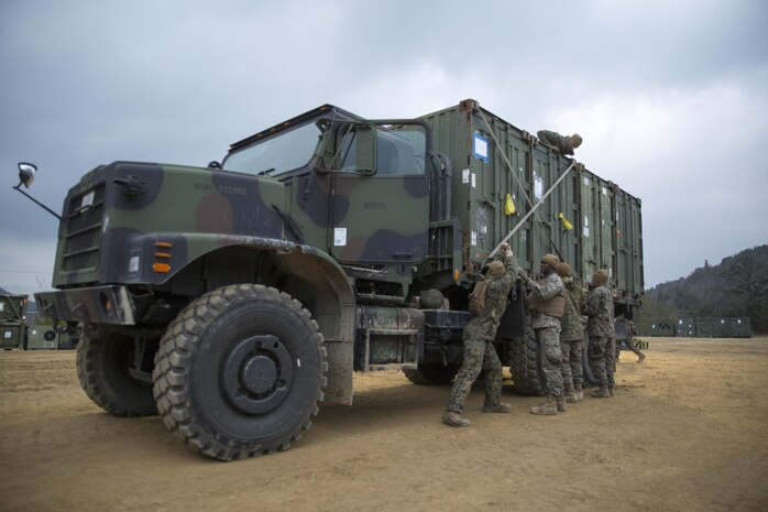 U.S. Marines with Marine Wing Support Squadron 171 secure quadcon shipping containers to the bed of a seven-ton medium tactical vehicle replacement during exercise Kamoshika Wrath 17-1 at Haramura Maneuver Area, Hiroshima, Japan, Jan. 27, 2017. The Marines worked through inclement weather conditions and a short timeline to build a 96-foot by 96-foot vertical takeoff and landing pad. The exercise is a biannual, unit-level training exercise that is primarily focused on establishing a forward operating base and providing airfield operation services. MWSS-171 trains throughout the year completing exercises like Kamoshika Wrath to enhance their technical skills, field experience and military occupational specialty capability. (U.S. Marine Corps photo by Cpl. Donato Maffin)