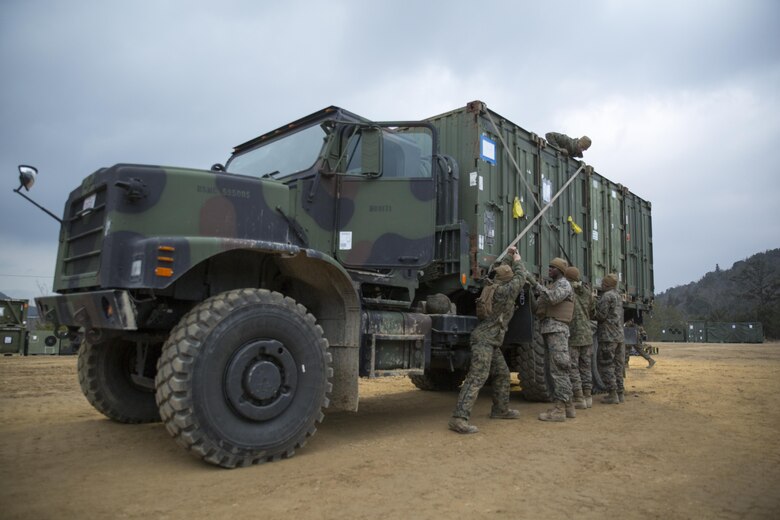 U.S. Marines with Marine Wing Support Squadron 171 secure quadcon shipping containers to the bed of a seven-ton medium tactical vehicle replacement during exercise Kamoshika Wrath 17-1 at Haramura Maneuver Area, Hiroshima, Japan, Jan. 27, 2017. The Marines worked through inclement weather conditions and a short timeline to build a 96-foot by 96-foot vertical takeoff and landing pad. The exercise is a biannual, unit-level training exercise that is primarily focused on establishing a forward operating base and providing airfield operation services. MWSS-171 trains throughout the year completing exercises like Kamoshika Wrath to enhance their technical skills, field experience and military occupational specialty capability. (U.S. Marine Corps photo by Cpl. Donato Maffin)