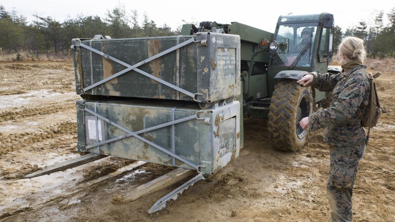 U.S. Marine Corps Lance Cpl. Jeni Ridgell, an expeditionary airfield technician with Marine Wing Support Squadron 171, directs Lance Cpl. Kevin Hodson, an engineer equipment operator with MWSS-171, as he moves crates of generation 2 aluminum matting during exercise Kamoshika Wrath 17-1 at Haramura Maneuver Area, Hiroshima, Japan, Jan. 27, 2017. The Marines worked through inclement weather conditions and a short timeline to build a 96-foot by 96-foot vertical takeoff and landing pad. The exercise is a biannual, unit-level training exercise that is primarily focused on establishing a forward operating base and providing airfield operation services. MWSS-171 trains throughout the year completing exercises like Kamoshika Wrath to enhance their technical skills, field experience and military occupational specialty capability.