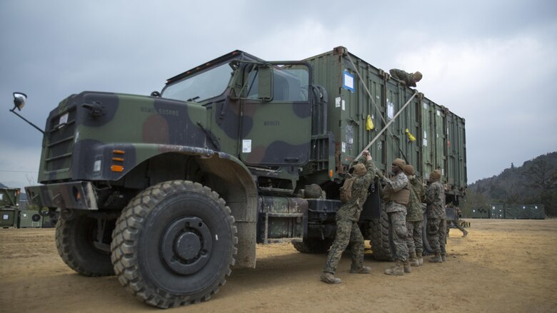 U.S. Marines with Marine Wing Support Squadron 171 secure quadcon shipping containers to the bed of a seven-ton medium tactical vehicle replacement during exercise Kamoshika Wrath 17-1 at Haramura Maneuver Area, Hiroshima, Japan, Jan. 27, 2017. The Marines worked through inclement weather conditions and a short timeline to build a 96-foot by 96-foot vertical takeoff and landing pad. The exercise is a biannual, unit-level training exercise that is primarily focused on establishing a forward operating base and providing airfield operation services. MWSS-171 trains throughout the year completing exercises like Kamoshika Wrath to enhance their technical skills, field experience and military occupational specialty capability.