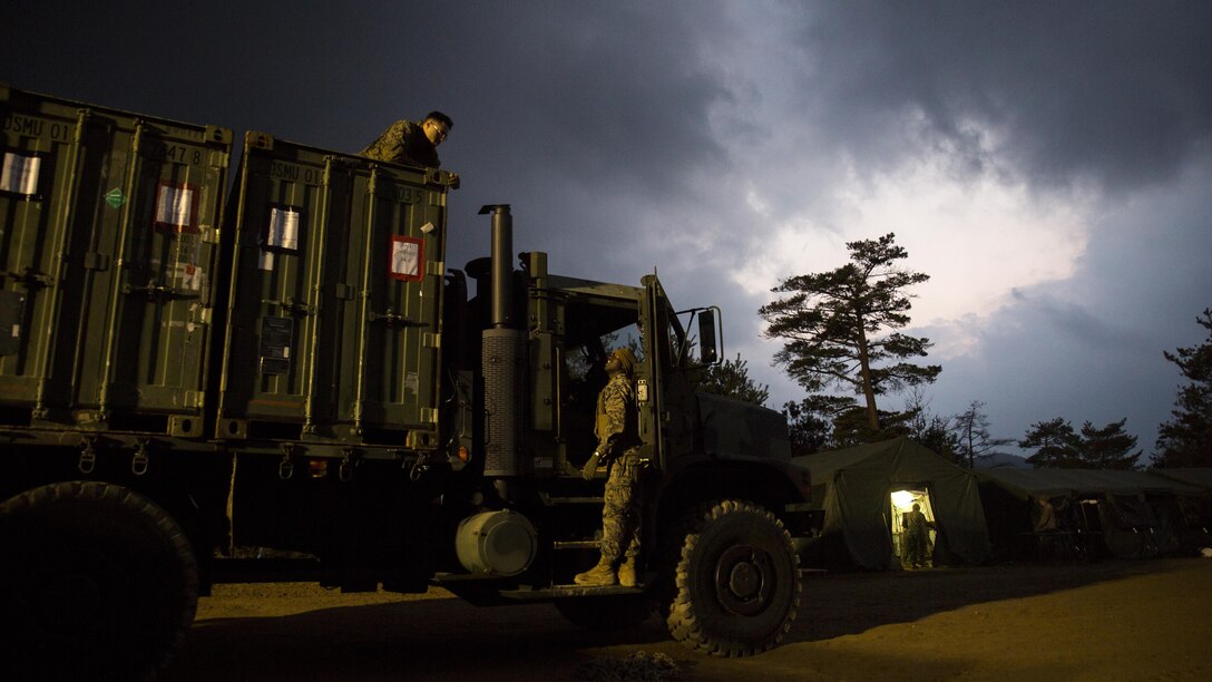 U.S. Marines with Marine Wing Support Squadron 171 communicate to each other after loading quadcon shipping containers onto a seven-ton medium tactical vehicle replacement during exercise Kamoshika Wrath 17-1 at Haramura Maneuver Area, Hiroshima, Japan, Jan. 27, 2017. The Marines worked through inclement weather conditions and a short timeline to build a 96-foot by 96-foot vertical takeoff and landing pad. The exercise is a biannual, unit-level training exercise that is primarily focused on establishing a forward operating base and providing airfield operation services. MWSS-171 trains throughout the year completing exercises like Kamoshika Wrath to enhance their technical skills, field experience and military occupational specialty capability.