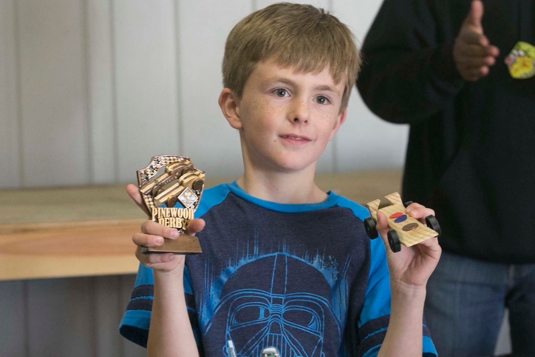 Wyatt Wheeler, son of Chief Petty Officer Casey Wheeler, senior enlisted advisor for Navy personnel, 7th Marine Regiment, displays his trophy and race car at the end of the annual Cub Scout Pinewood Derby at the Armed Services YMCA Scout Hut, Jan. 21, 2017. (U.S. Marine Corps photo by Cpl. Thomas Mudd)