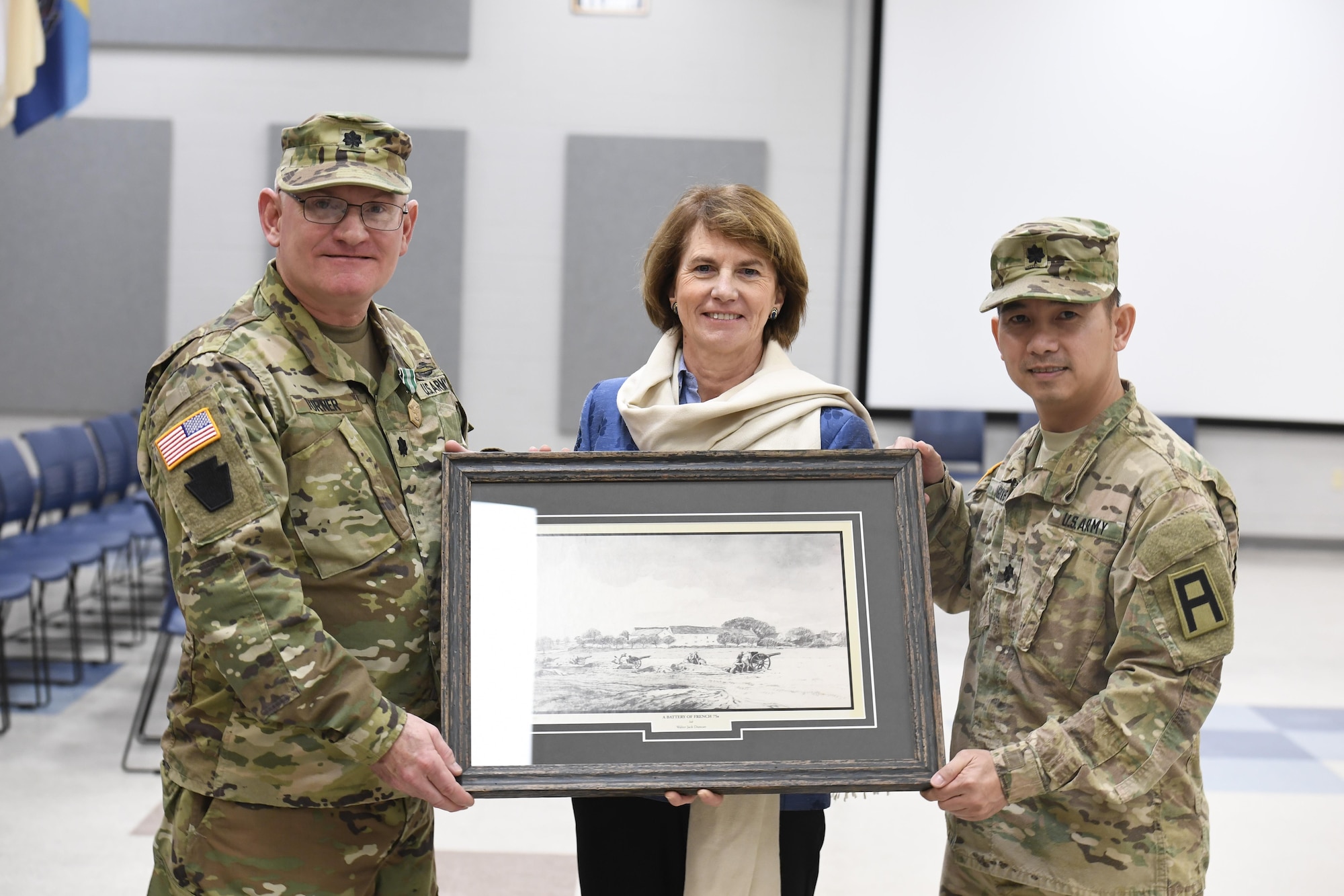 Outgoing 3-313th Logistics Support Battalion commander Lt. Col. John Turner Jr. and incoming commander Lt. Col. Binh Nguyen present Madame Anne de Broca-Hoppenot a painting of the unit fighting in France during World War I. Turner Jr. relinquished command to Nguyen during the change of command ceremony following the re-awarding of the Croix de Guerre to the unit by Broca-Hoppenot.