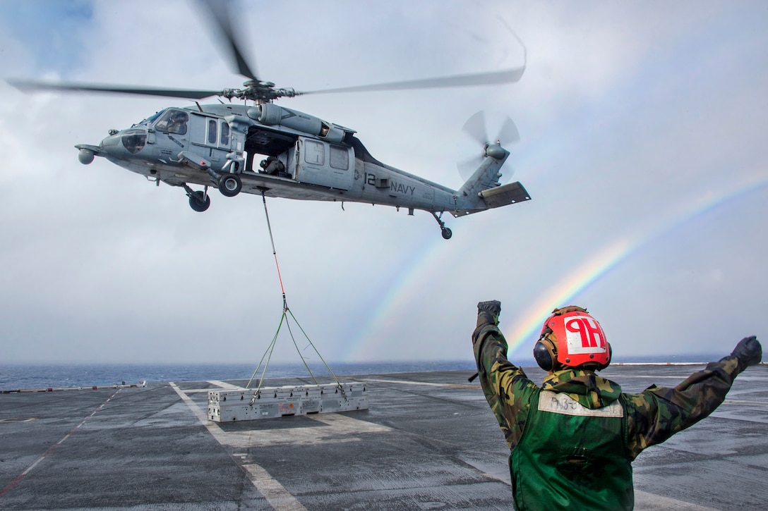 With a double rainbow in the background, Navy Seaman Rebecca Geissinger uses hand signals to direct the crew of an MH-60S Seahawk helicopter during a vertical replenishment with the aircraft carrier USS Carl Vinson and the Military Sealift Command dry cargo and ammunition ship USNS Charles Drew in the Pacific Ocean, Jan. 28, 2017. Geissinger is an aviation ordnanceman airman assigned to Helicopter Sea Combat Squadron 4. Navy photo by Petty Officer 2nd Class Sean M. Castellano