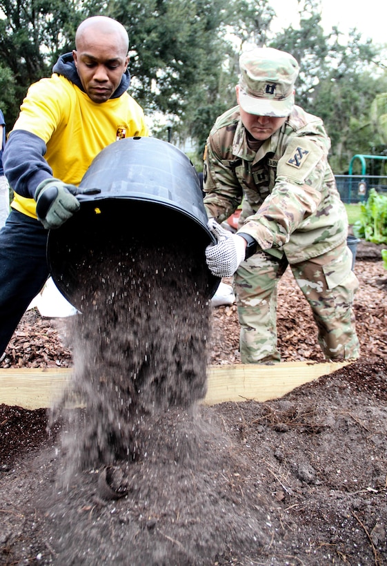 Army Sgt. Maj. Marcus F. Alfred (left), a Kissimmee, Fla., native serving as the S-4 (logistics) sergeant major, 641st Regional Sustainment Group, 143d Sustainment Command (Expeditionary), and Army Capt. Josh C. Agnew (right), a Chippewa Falls, Wisch., native serving operations officer, 143d ESC, pour fresh soil into a newly installed garden bed Jan. 27, 2017, at the Colonialtown North Community Garden in Orlando, Fla. Alfred, Agnew and five other Army Reserve Soldiers joined scores of volunteers from the Orlando community to help bring the garden back to its former, greener glory. Directed by Green Works Orlando in conjunction with the NFL’s Environmental Program, the garden’s revival was one of the many community projects both organizations managed to lighten the environmental footprint produced by the tens of thousands of football fans who have flocked to The City Beautiful to watch the NFL’s first Pro Bowl game to take place in the Continental U.S. since 1979. 