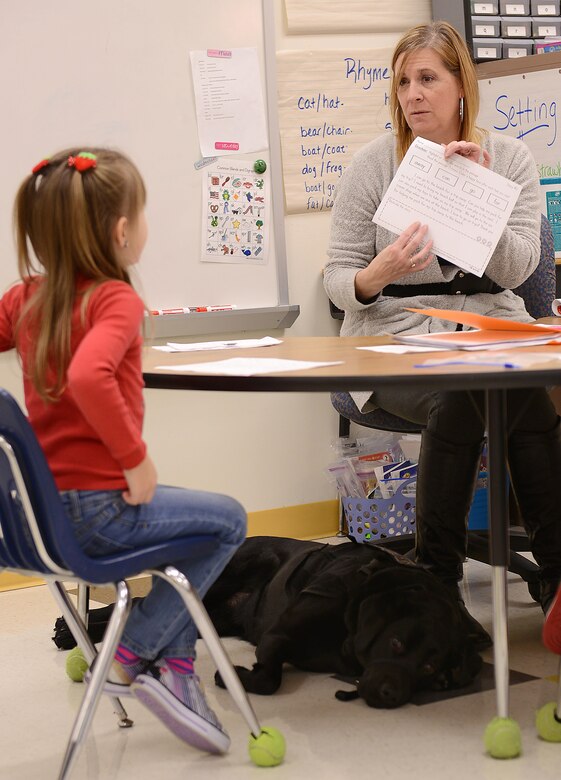 AudreeAna Johns, age six, daughter of U.S. Army Sgt. Matthew Johns, 221st Military Police Detachment military police officer, works with Kelly Craven, Gen. Stanford Elementary School special education teacher, as Hope, AudreeAna’s service dog, lies at her feet at Joint Base Langley-Eustis, Va., Jan. 24, 2017. Before AudreeAna arrived to the school, her teachers worked with her classmates to help them understand a service animal’s purpose. (U.S. Air Force photo by Staff Sgt. Teresa J. Cleveland)