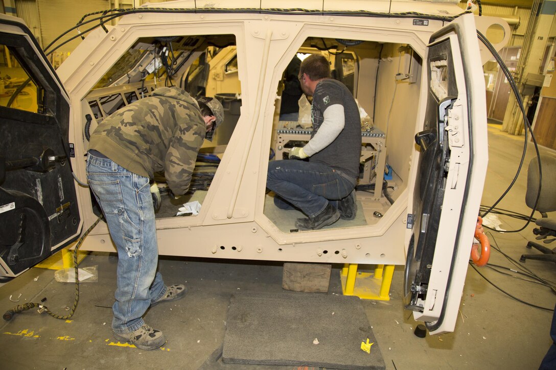 (Left) Kevin Leonard, a native of Newport Beach, Calif., and William Marler, from Victorville, Calif., heavy mobile equipment mechanics, work on the interior of the crew capsule for the M-ATV, also known as a Mine Resistant Ambush Protected All Terrain Vehicles, at Production Plant Barstow, Marine Depot Maintenance Command, Jan. 12. The crew cab is heavily protected by reinforced armor to help the occupants survive a blast from powerful improvised explosive devices.
