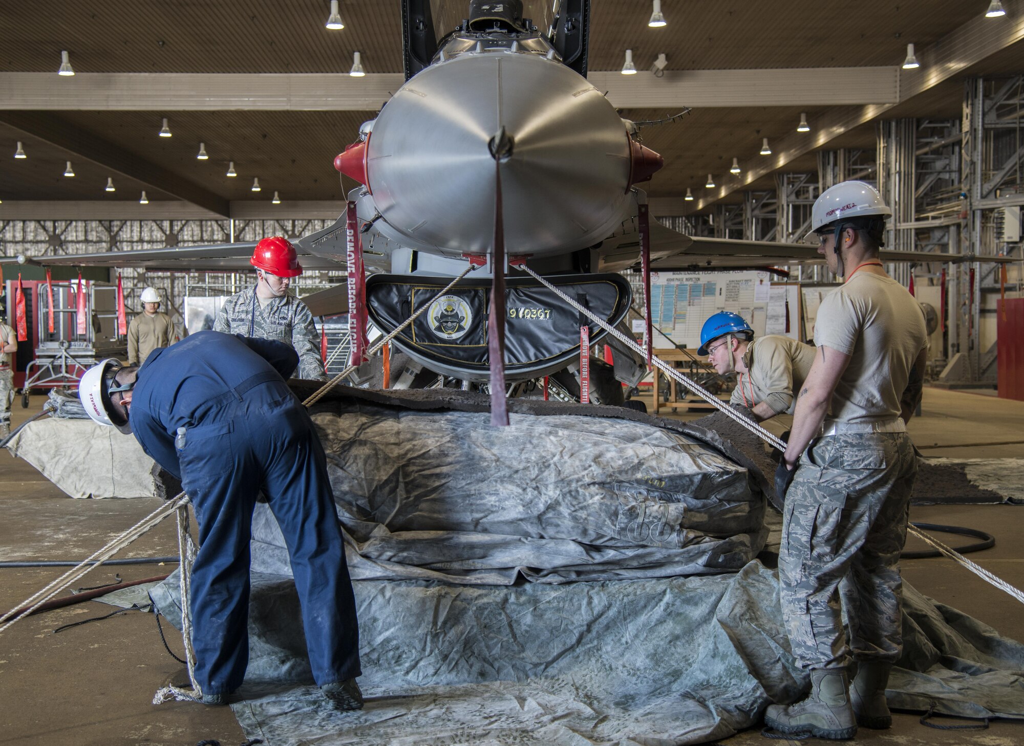 Airmen with the 35th Maintenance Squadron crashed, damaged, disabled aircraft recovery unit center a lifting bag while being inflated on a pallet build up at Misawa Air Base, Japan, Jan. 28, 2017. These Airmen respond to aircraft incidents when an aircraft needs to be lifted to retract landing gear or moved off an active runway, enabling normal mission operations to resume. (U.S. Air Force photo by Senior Airman Brittany A. Chase)