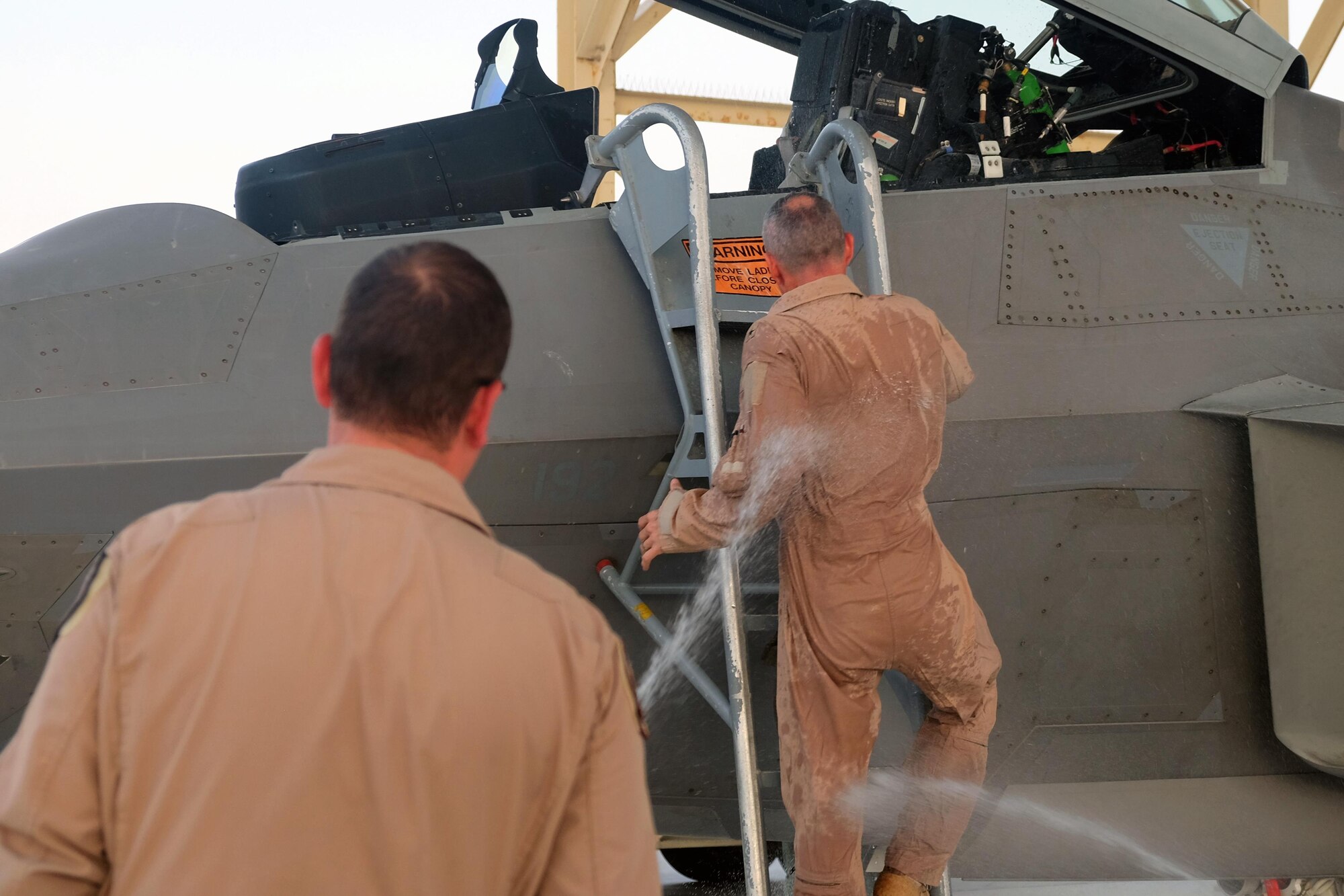Brig. Gen. Charles S. Corcoran, 380th Air Expeditionary Wing commander, climbs down from an F-22 Raptor while being sprayed with water at his fini-flight June 30, 2017, at an undisclosed location in southwest Asia. After his tenure as 380 AEW commander, Corcoran is slated to assume the position of Deputy Chief of Staff for NATO Air Operations at Allied Air Command Headquarters, Ramstein, Germany. (U.S. Air Force photo by Senior Airman Preston Webb)