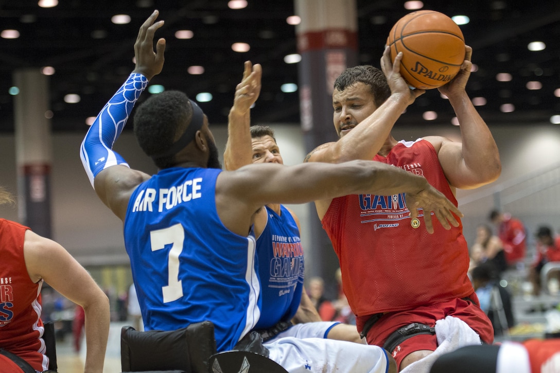 Marine Corps Lance Cpl. Mathew Grashen keeps the ball away from a pair of Air Force defenders during the wheelchair basketball preliminaries at the 2017 Department of Defense Warrior Games in Chicago, June 30, 2017. DoD photo by EJ Hersom