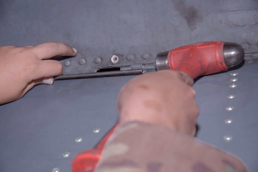 Airman Kiley Foulke, a 386th Expeditionary Maintenance Squadron combat metals team member, hammers in a hinge pin on a recently repaired C-130H landing gear door at an undisclosed location in Southwest Asia, June 23, 2017. (U.S. Air Force photo by Master Sgt. Eric M. Sharman)