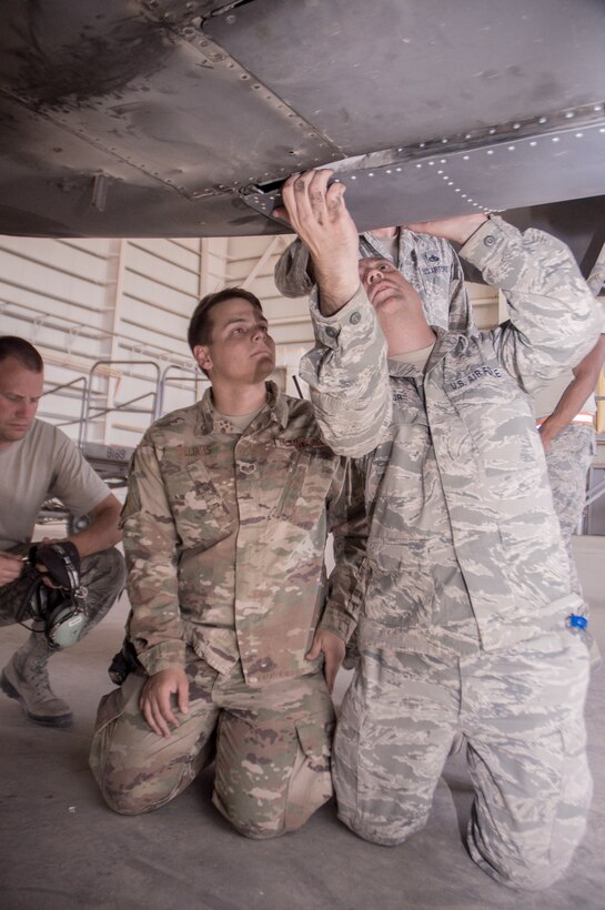 Master Sgt. Daniel Taylor, 386th Expeditionary Maintenance Squadron combat metals flight chief, checks a newly repaired C-130H landing gear door for fit after installation as Senior Airman Andrew Williams, a combat metals team member, looks on during an installation operation at an undisclosed location in Southwest Asia, June 23, 2017. (U.S. Air Force photo by Master Sgt. Eric M. Sharman)