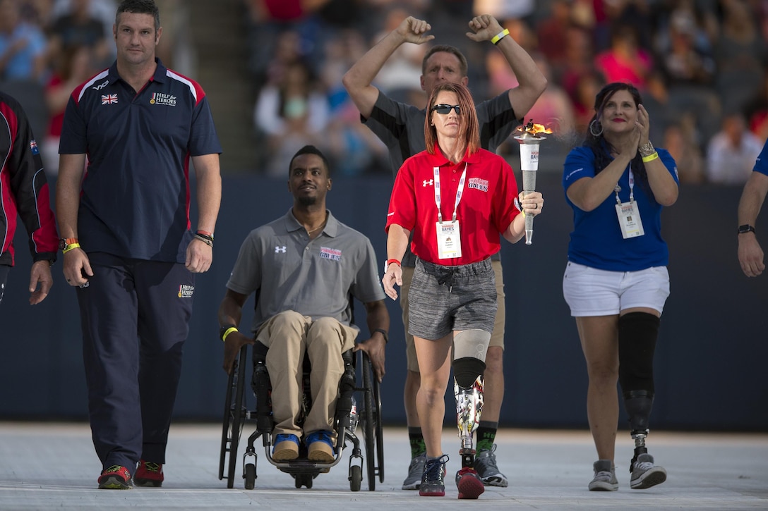 Medically retired Marine Corps Lance Cpl. Sarah Rudder carries the 2017 Department of Defense Warrior Games torch into Soldier Field in Chicago, July 1, 2017. The DoD Warrior Games are an annual event allowing wounded, ill and injured service members and veterans to compete in Paralympic-style sports. DoD photo by EJ Hersom