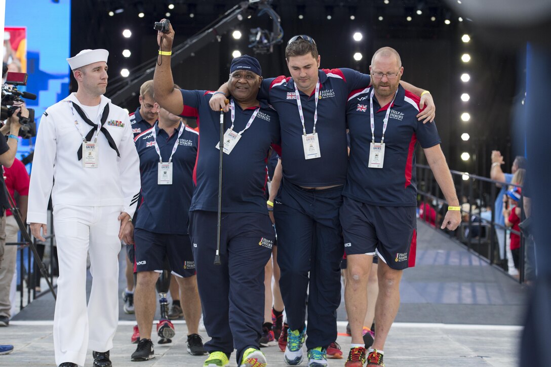 Army Cpl. Tiko Morgan, left, and Mark Airey, a sports lead, help teammate Army Cpl. Daniel Bingley as team United Kingdom enters the opening ceremonies of the 2017 Department of Defense Warrior Games at Soldier Field in Chicago, July 1, 2017. DoD photo by EJ Hersom