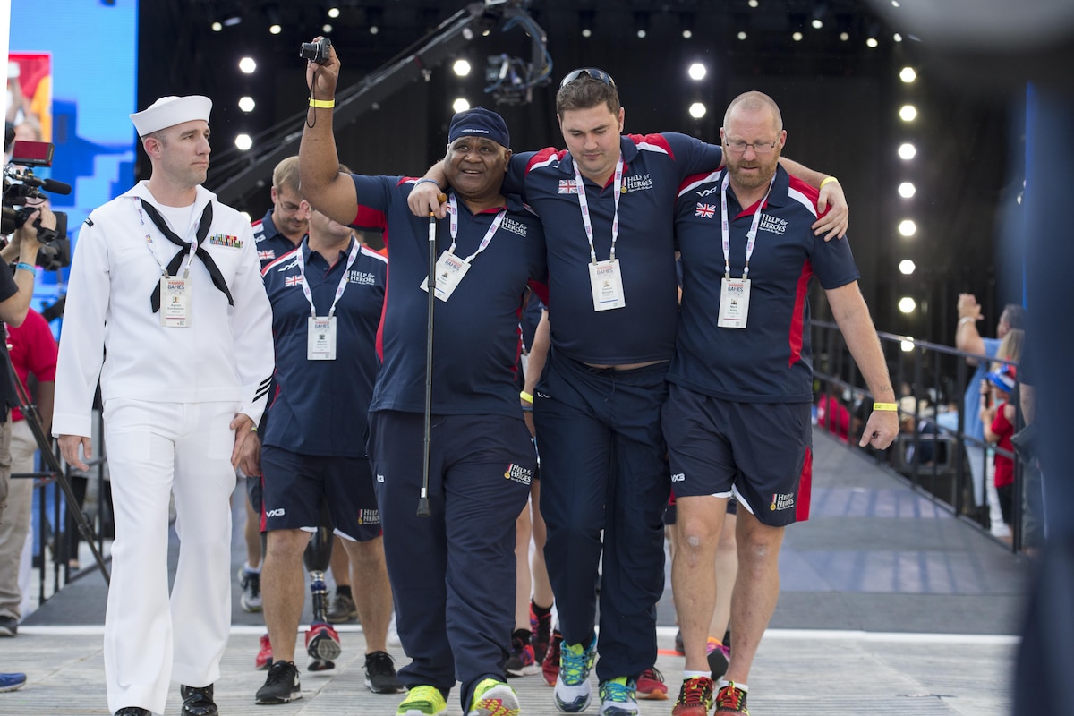 Army Cpl. Tiko Morgan, left, and Mark Airey, a sports lead, help teammate Army Cpl. Daniel Bingley as team United Kingdom enters the opening ceremonies of the 2017 Department of Defense Warrior Games at Soldier Field in Chicago, July 1, 2017. DoD photo by EJ Hersom