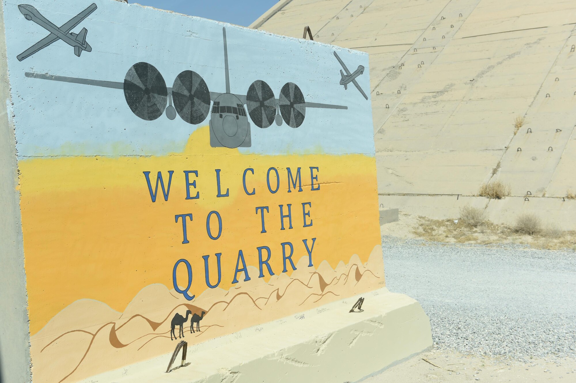 A T-wall stands at the entrance to the 386th Air Expeditionary Wing flightline area welcoming Airmen to the “Quarry” at an undisclosed location in Southwest Asia, June 27, 2017. The 386th Expeditionary Maintenance Group hosted a “Rock to Quarry” connection tour as an opportunity for Airmen, whose duties do not typically involve flightline access, to see how their job supports the overall wing’s flying mission.  (U.S. Air Force photo by Tech. Sgt. Jonathan Hehnly)
