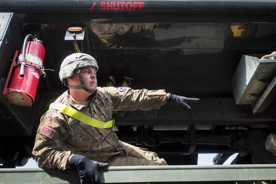 Army Pvt. Aaron McCay asks a team member to hand him a breaker bar while securing a vehicle to a flatbed trailer at Joint Base Elmendorf-Richardson, Alaska, June 28, 2017. McCay, who's supporting an Air Force exercise, is assigned to the 109th Transportation Company. Air Force photo by Justin Connaher