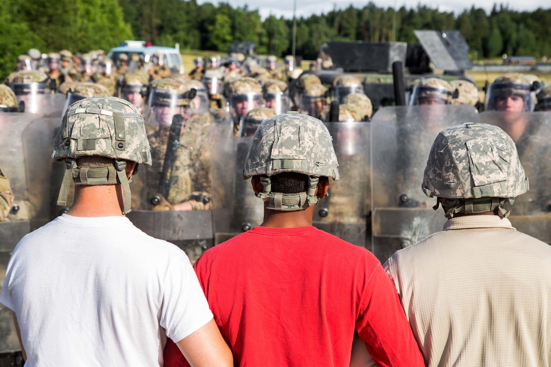 U.S. soldiers role-playing as a hostile crowd block a road while additional soldiers conduct a riot control scenario during a Kosovo Force mission rehearsal exercise at the Joint Multinational Readiness Center in Hohenfels, Germany, June 30, 2017. The soldiers are assigned to the 1st Battalion, 4th Infantry Regiment. Army photo by Spc. Randy Wren