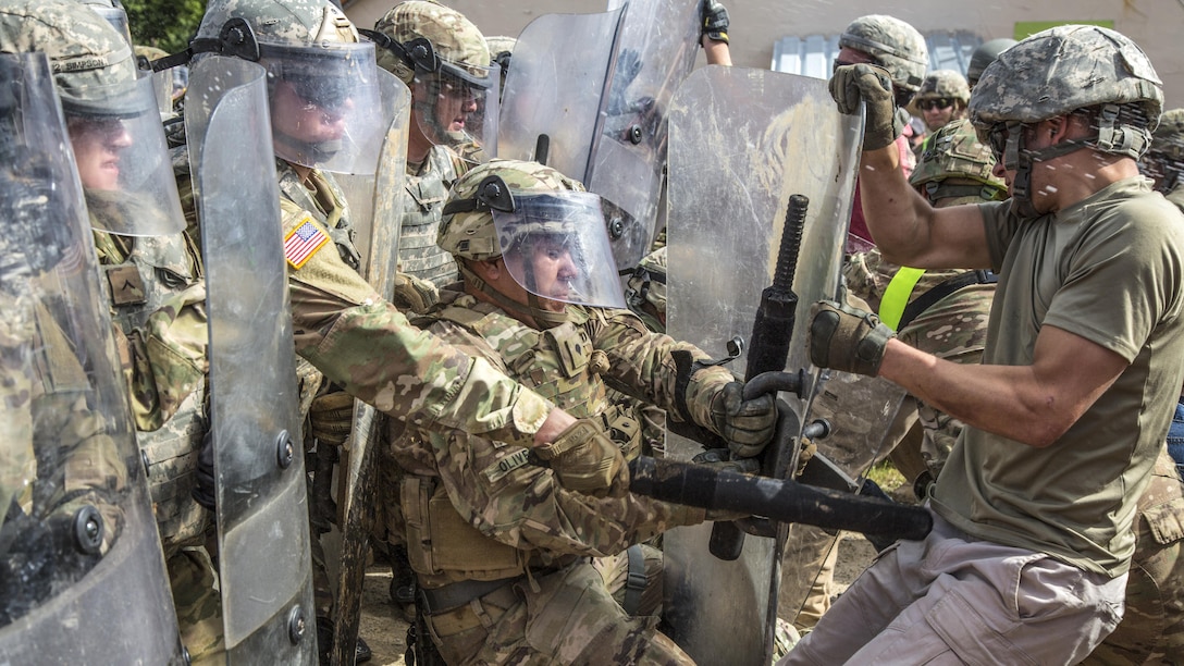 A soldier, center left, prevents a fellow soldier role-playing as a hostile civilian from taking his riot shield during a crowd control training scenario as part of a mission rehearsal exercise at the Joint Multinational Readiness Center in Hohenfels, Germany, June 30, 2017. The exercise aimed to prepare the 39th Infantry Brigade Combat Team for a deployment to support civil authorities in Kosovo. Army photo by Spc. Randy Wren