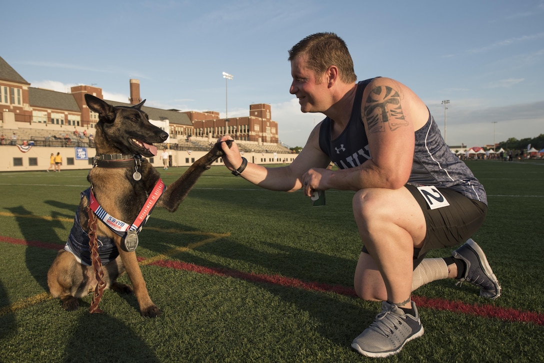 Navy veteran Ron Condrey gets a high-five from Via, his military service dog, after winning the silver medal in a track event during the 2017 Department of Defense Warrior Games in Chicago, July 2, 2017. DoD photo by Roger L. Wollenberg