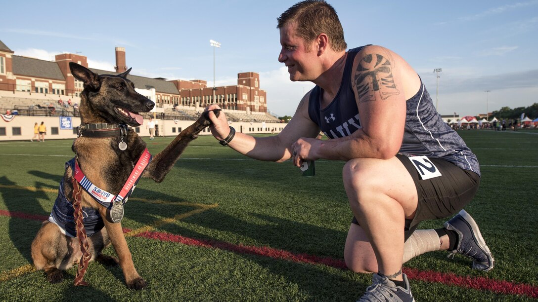 Navy veteran Ron Condrey high-fives his military service dog, Via, after winning a silver medal in a track event during the 2017 Department of Defense Warrior Games in Chicago, July 2, 2017. DoD photo by Roger L. Wollenberg