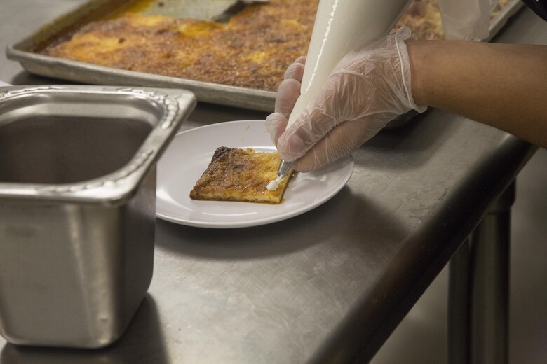 Lance Cpl. Carlos Amaya, Chef of the Quarter participant, prepares his teams flan dish for the judges during the Chef of the Quarter competition at Phelps Mess Hall aboard Marine Corps Air Ground Combat Center Twentynine Palms, Calif., June 21, 2017. The competition gave Marines and Sodexo chefs the ability to cook against each other in a friendly competition and break away from the very ridged routine schedule. (U.S. Marine Corps photo by Cpl. Thomas Mudd)