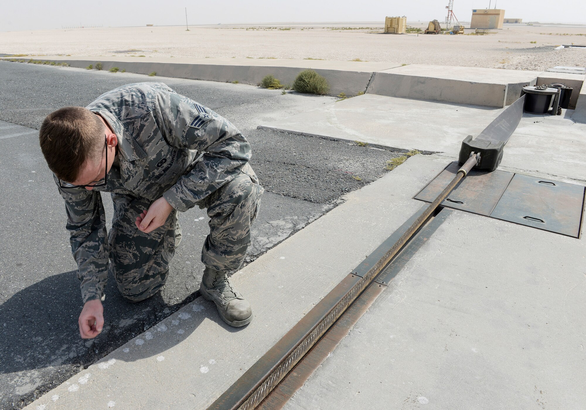 U.S. Air Force Senior Airman Thomas Smith, airfield management shift lead assigned to the 379th Expeditionary Office of Strategic Services, picks up small stones from the runway during a general runway inspection at Al Udeid, Air Force Base, Qatar, June 7, 2017. Airfield Management oversees the 23.3 million square feet of airfield at Al Udeid in addition to overseeing the airfield driving program and filing all flight plans for flights arriving to and departing from the base. (U.S. Air National Guard photo by Tech. Sgt. Bradly A. Schneider/Released)