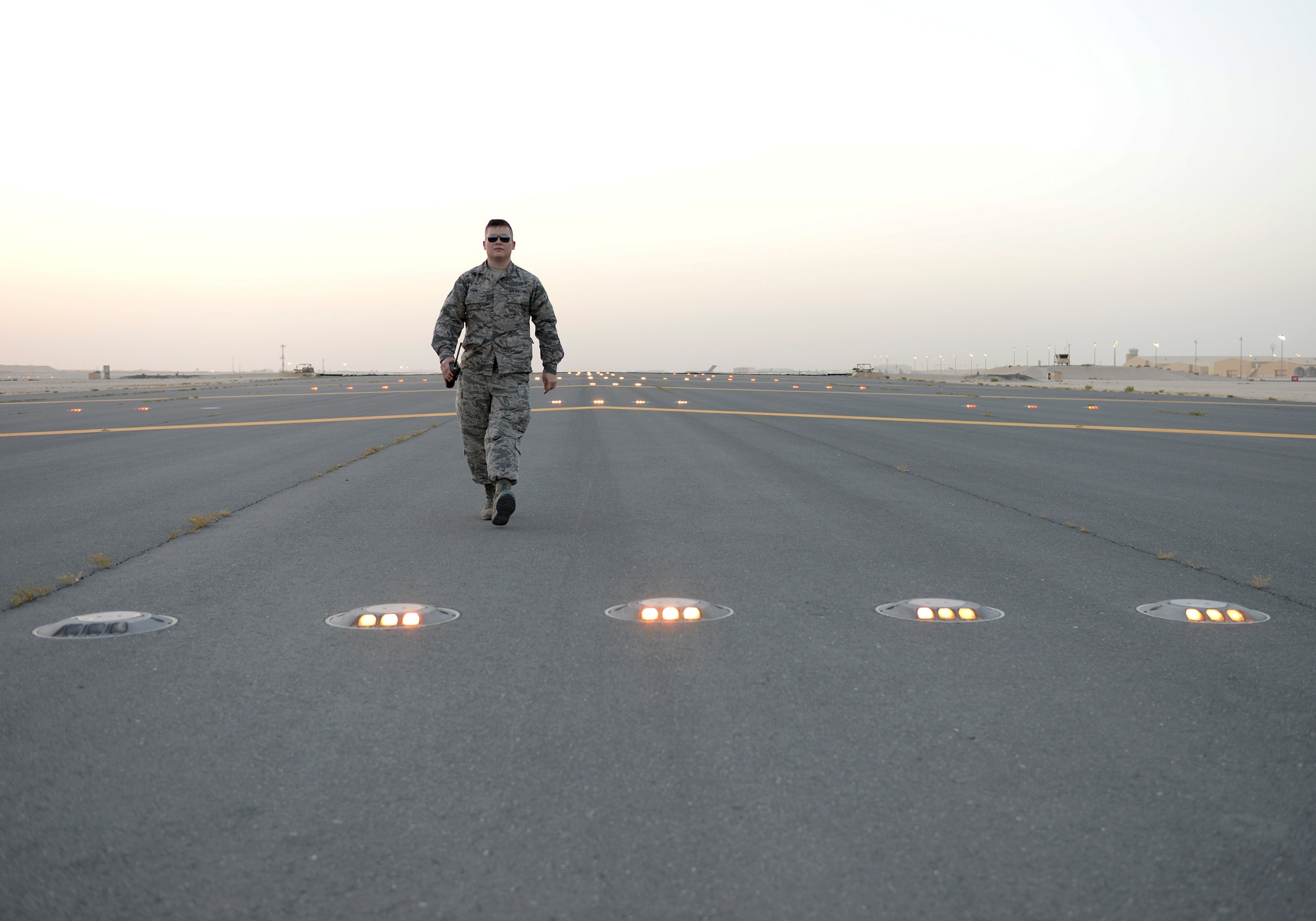 U.S. Air Force Senior Airman William Terry, airfield management shift lead assigned to the 379th Expeditionary Office of Strategic Services, walks the runway at dusk during a lighting check at Al Udeid, Air Force Base, Qatar, June 22, 2017. Airfield Management oversees the 23.3 million square feet of airfield at Al Udeid in addition to overseeing the airfield driving program and filing all flight plans for flights arriving to and departing from the base. (U.S. Air National Guard photo by Tech. Sgt. Bradly A. Schneider/Released)