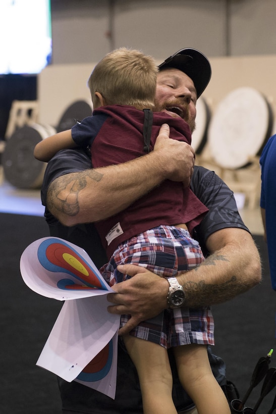 Finn Lindstrom, 8, greets his father medically retired Army Sgt. First Class Joshua Lindstrom of Team Special Operations Command after Joshua won gold during the 2017 Department of Defense Warrior Games archery competition in Chicago, July 3, 2017. The Warrior Games are an annual event allowing wounded, ill and injured service members and veterans to compete in Paralympic-style sports. DoD photo by EJ Hersom