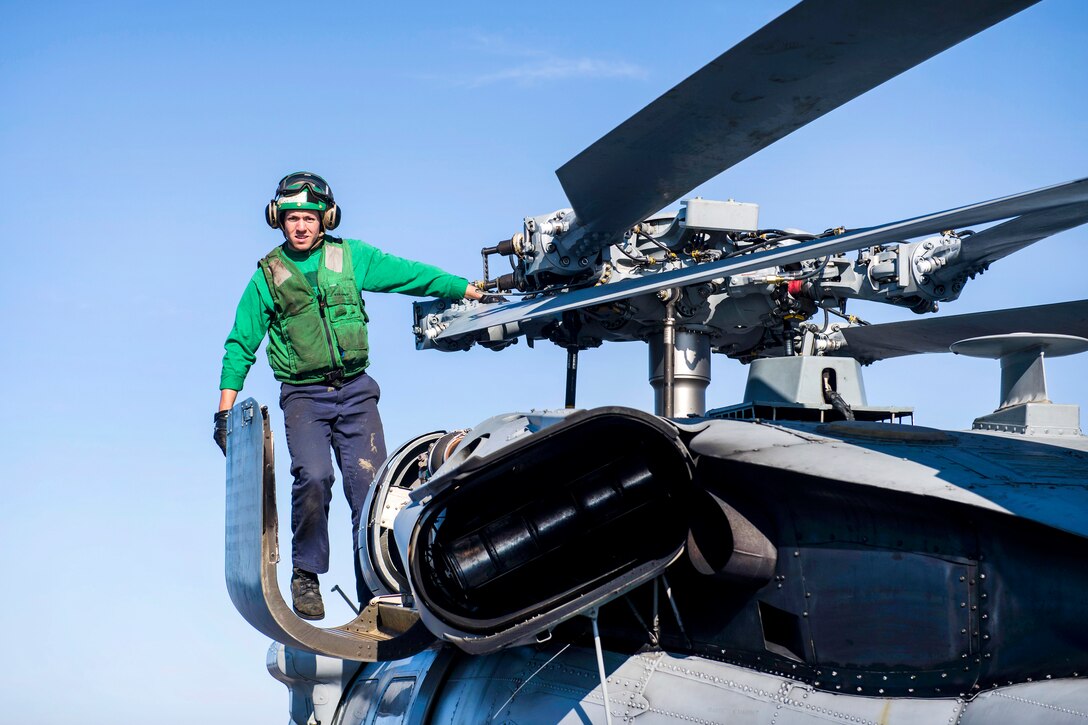 Navy Petty Officer 3rd Class Jake Kelley scales an MH-60S Sea Hawk helicopter to perform maintenance on the main rotor aboard the aircraft carrier USS Dwight D. Eisenhower in the Atlantic Ocean, June 25, 2017. Kelley is an aviation machinist's mate. Navy photo by Seaman Jessica L. Dowell