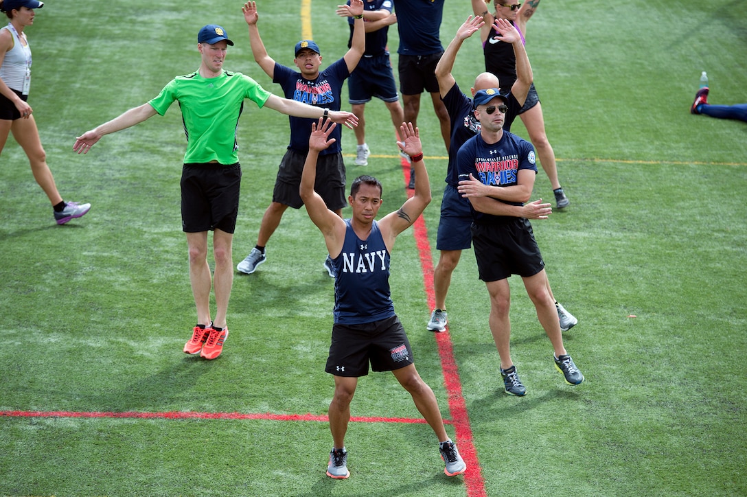 Navy Petty Officer 1st Class Romulo Urtula, front, leads a warm up exercise during track practice for the 2017 Department of Defense Warrior Games in Chicago, June 30, 2017. DoD photo by EJ Hersom