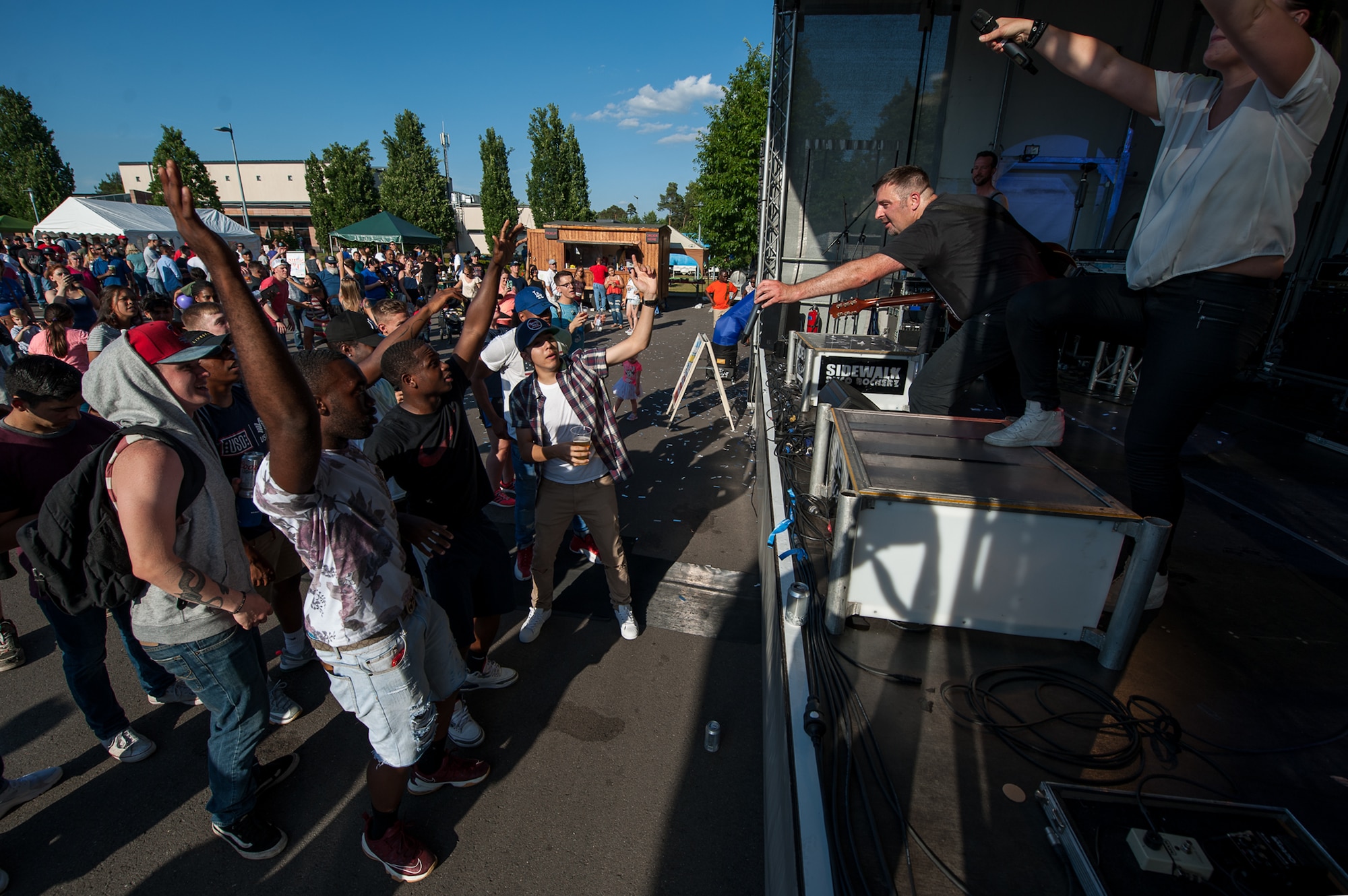 The vocalist from Sidewalk-Coverband hands his microphone to the crowd while playing an American rock song during Freedom Fest at the Enlisted Club parking lot on Ramstein Air Base, Germany, July 4, 2017. The singer encouraged the crowd to sing along with them during the Independence Day celebration. (U.S. Air Force photo by Senior Airman Devin Boyer)